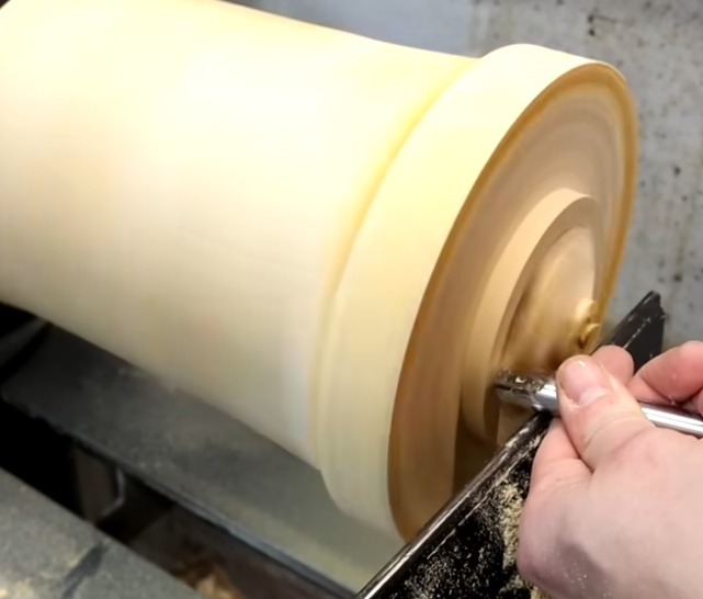 Wood turning machining on a lathe creating a smooth cylindrical solid wood