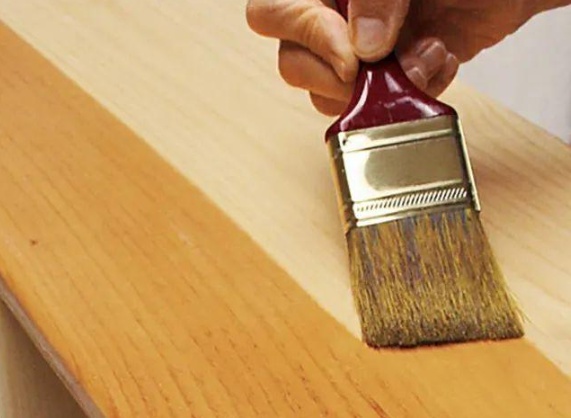 Applying wood stain with a brush to enhance natural grain